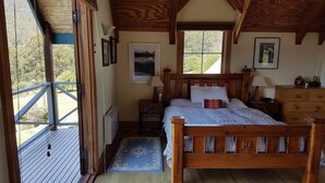 A wooden bedroom with a bed, nightstands, a dresser, and two windows. - Fantastic getaway for family or friends with spectacular views. (Snug)