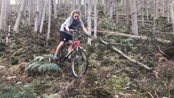 Una persona montando una bicicleta de montaña por un área boscosa con árboles y maleza.