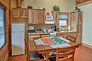 Uma cozinha compacta com armários de madeira, geladeira, micro-ondas, torradeira e uma mesa de jantar posta com jogos americanos e pratos.