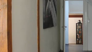 Ein Flur mit Holztürrahmen, weißem Teppich, einem Bücherregal und einem Gemälde an der Wand.