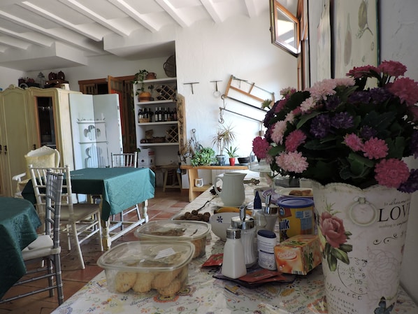 A cozy dining area with a table set for two, a chair, and a vase of flowers.