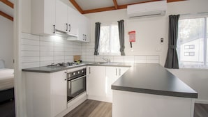A modern kitchen with white cabinetry, a built-in oven, and a granite countertop. - BIG4 Tiny Away Stay – Seymour Riverside (Seymour)