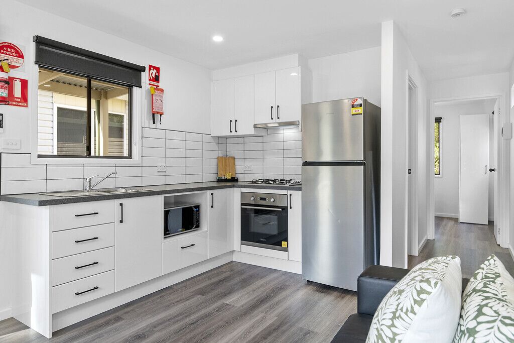 A modern kitchen with white cabinets, a stainless steel refrigerator, a microwave, and an oven.