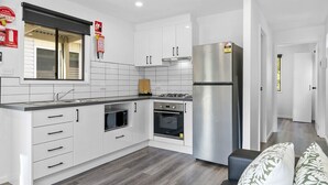 Une cuisine moderne avec des meubles blancs, un réfrigérateur en acier inoxydable, un four à micro-ondes et un four traditionnel.