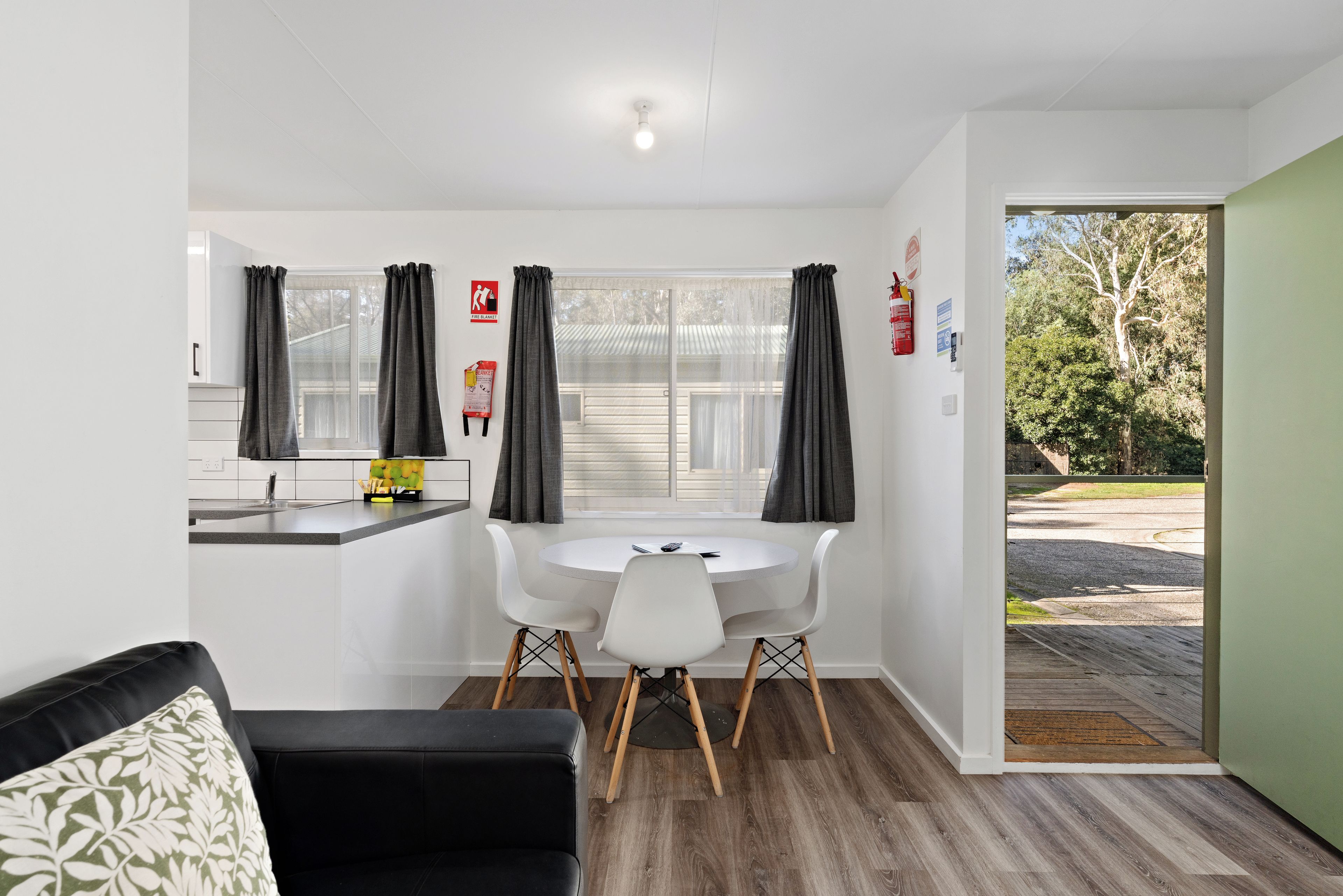 A compact living space with a kitchenette, a dining area, and a view of the outdoors.