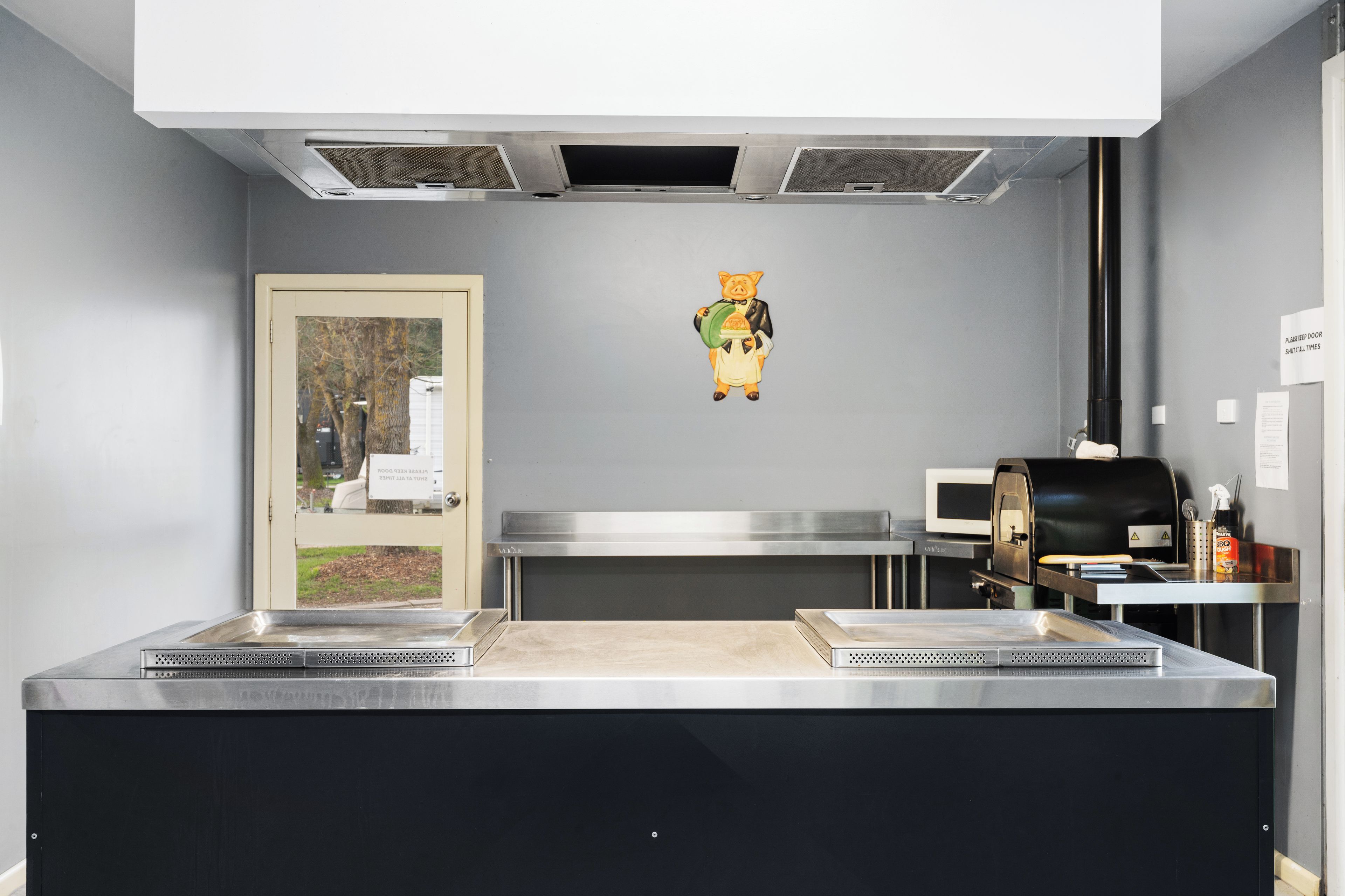 A kitchen with stainless steel appliances, a microwave, and a grill.