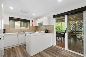 A modern kitchen with white cabinets, a central island, and a sliding glass door leading to an outdoor patio.