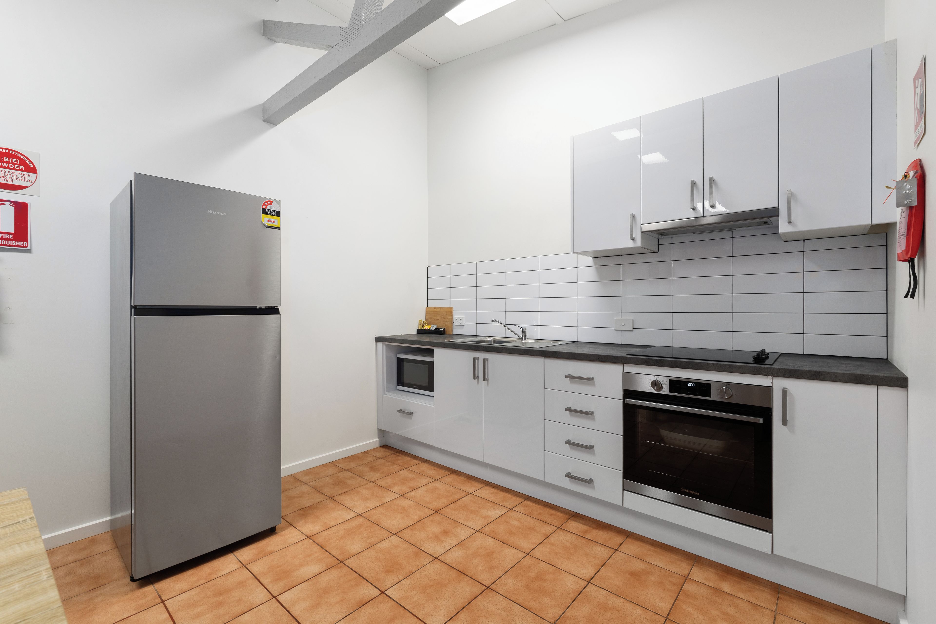 A modern kitchen with stainless steel appliances, white cabinetry, and a tiled backsplash.