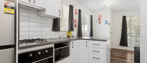 A modern kitchen with white cabinets, a stainless steel stove, and a microwave.