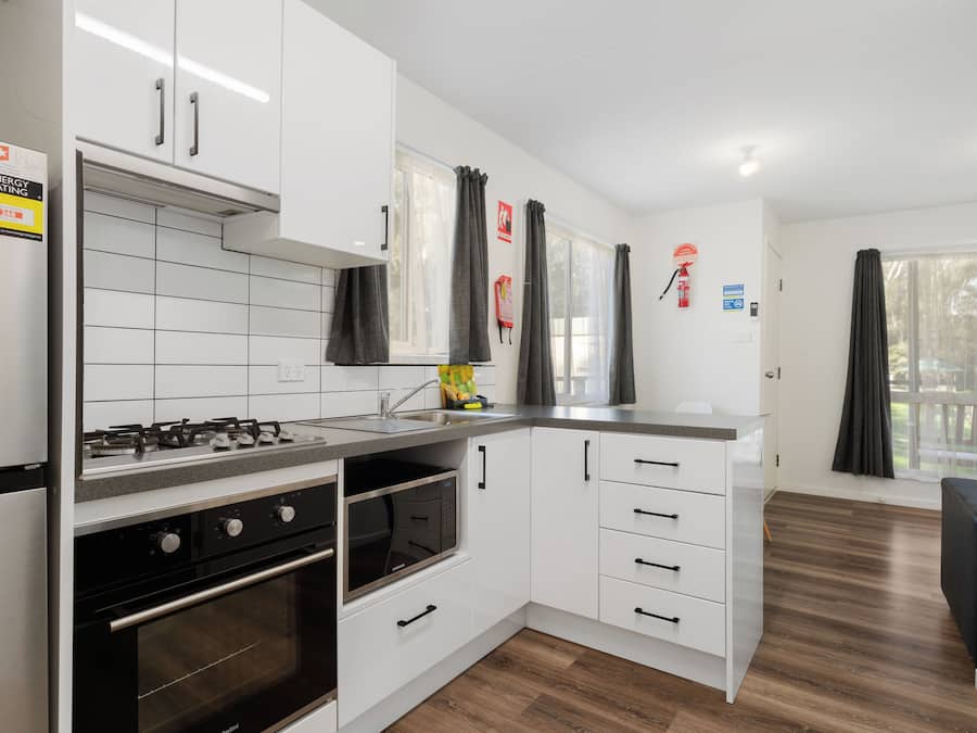 A modern kitchen with white cabinets, a stainless steel stove, and a microwave.