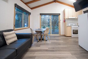 A compact kitchen with a dining area, a sofa, and a TV.
