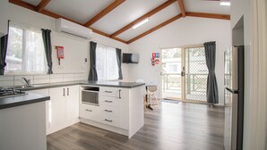 Une cuisine moderne avec des meubles blancs, un four à micro-ondes encastré et une grande fenêtre avec des rideaux.