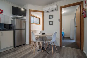 Een compacte keuken met een koelkast, magnetron en een flatscreen-televisie boven het aanrecht.