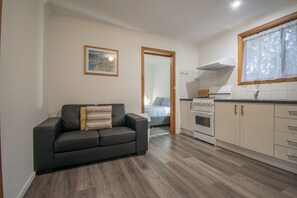 Een moderne keuken met een inbouwoven, een eetgedeelte met tafel en stoelen, en een woonkamer met een bank.