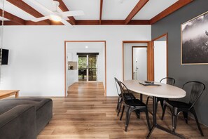 Ein modernes Interieur mit einer Essecke, die einen runden Tisch und Stühle, Holzboden und einen Deckenventilator zeigt.