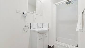 A modern bathroom with a white sink, mirror, and shower.