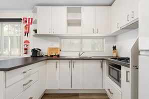 Et moderne køkken med hvide skabe, en rustfri stålvask og en indbygget ovn.