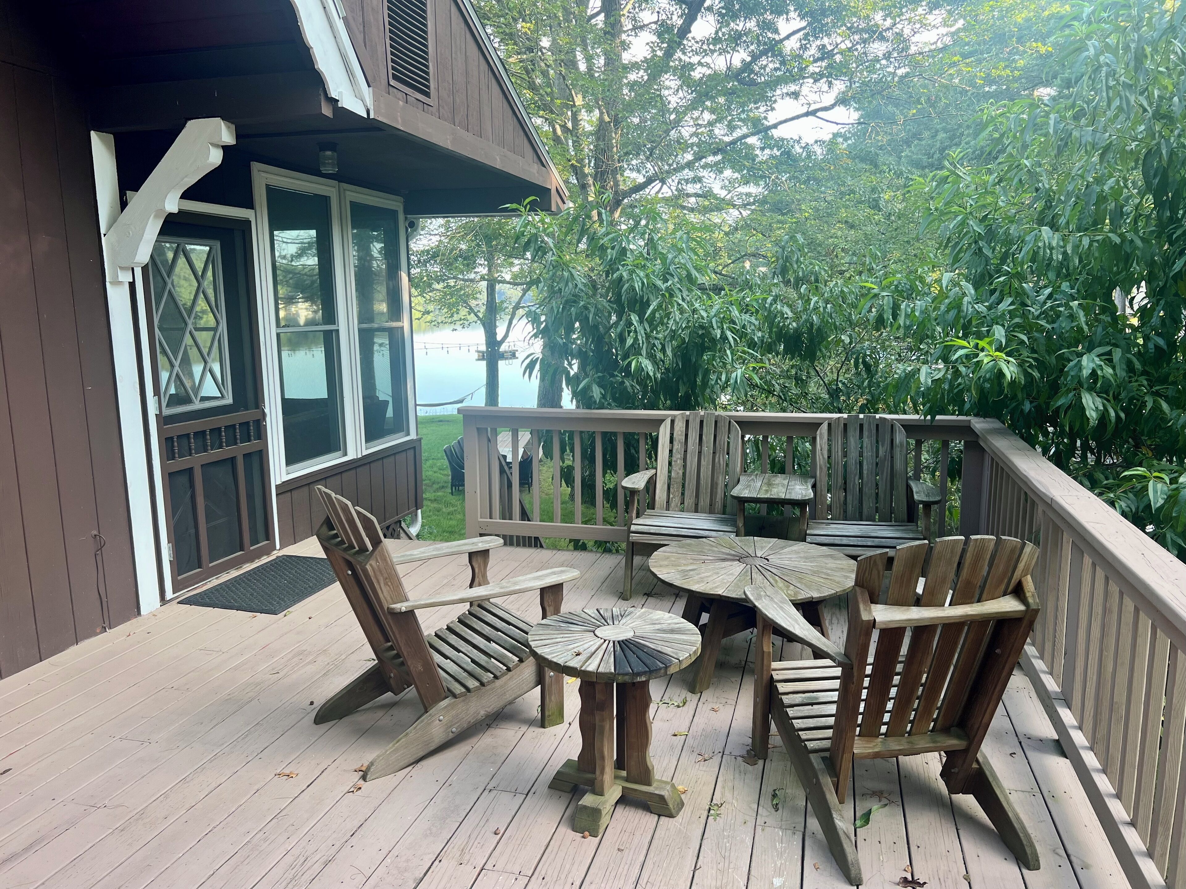 Eine Holzterrasse mit Tisch und Stühlen mit Blick auf einen See.