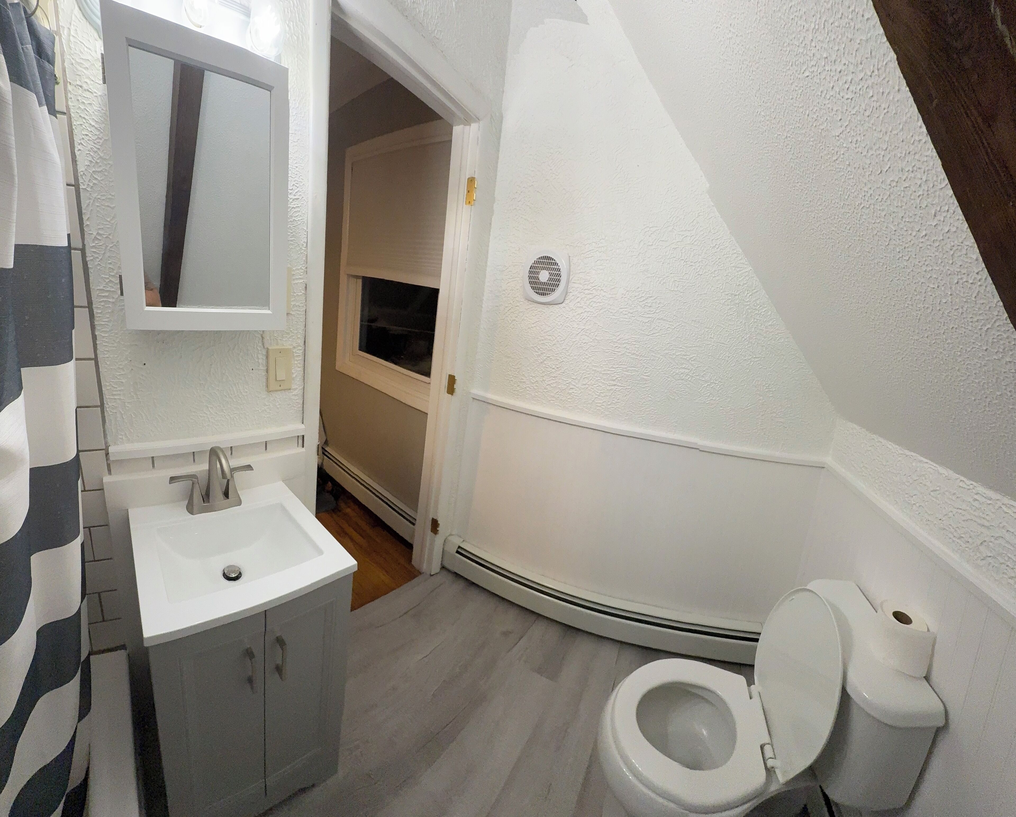 Un baño con lavamanos, espejo e inodoro blancos.