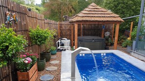 Ein Garten mit Swimmingpool, Holzzaun und Whirlpool.