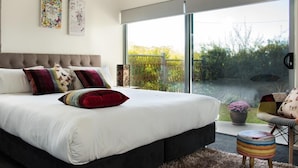 Ein modernes Schlafzimmer mit großem Bett, Blick ins Freie und einer kleinen Sitzecke.