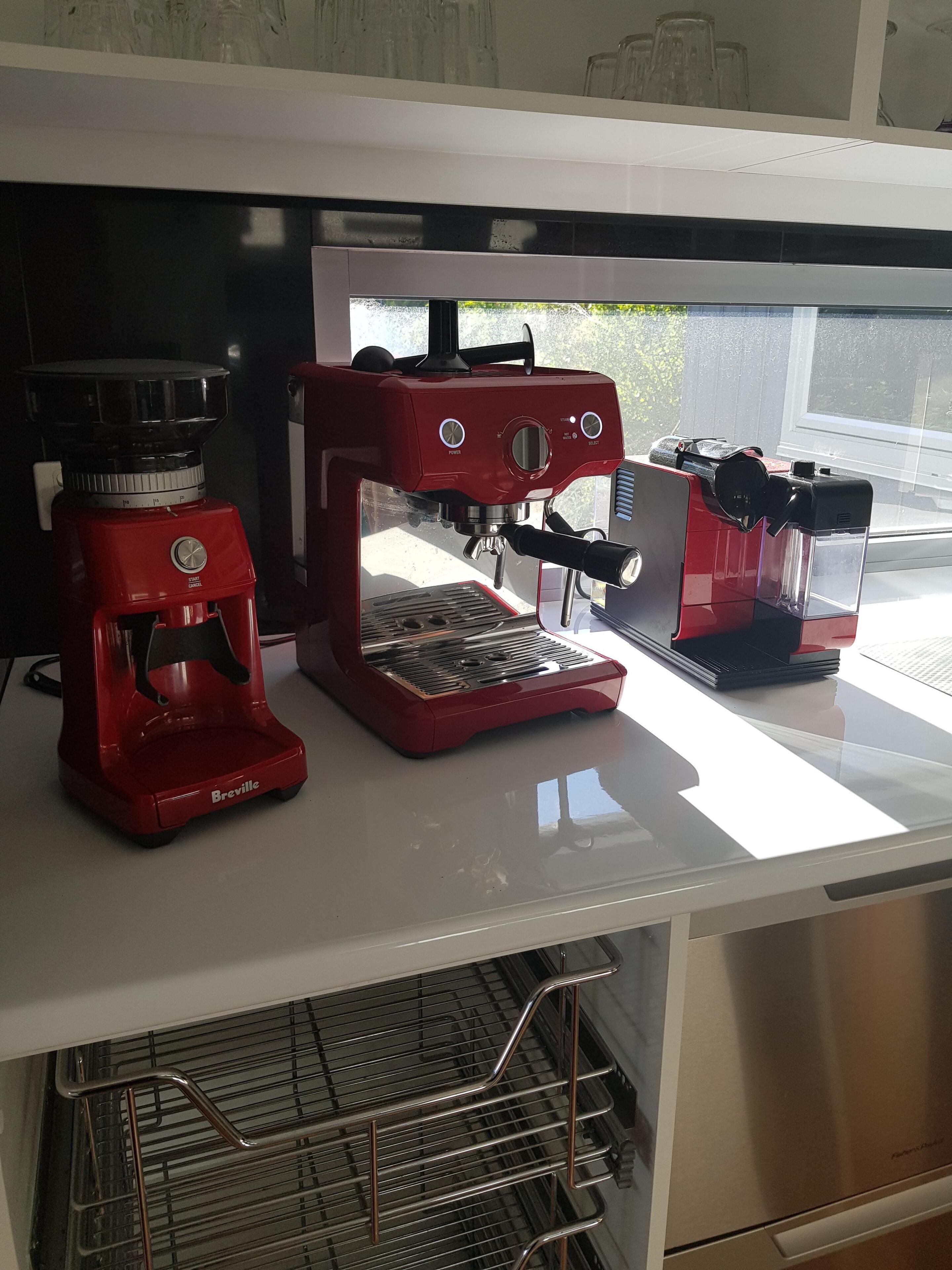 A kitchen with a Breville espresso machine and a coffee grinder on a white countertop.