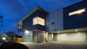 Ein modernes, zweistöckiges Gebäude mit Garage und überdachtem Außenbereich.