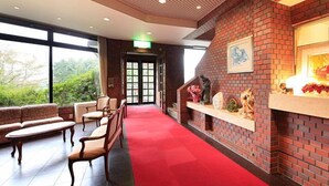 A lobby with a red carpet, brick walls, a fireplace, and a large window. - morinoakari (Hakone)