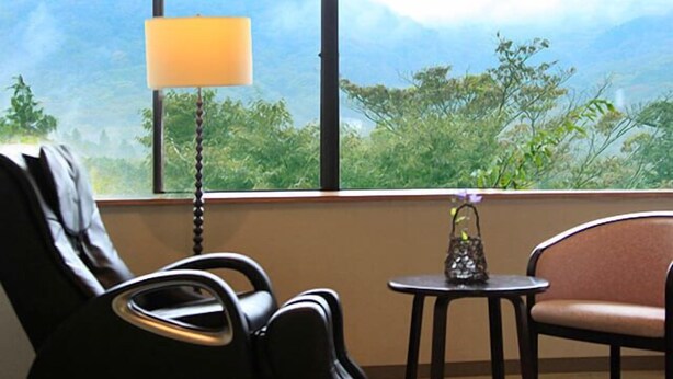 A room with a view of mountains through large windows, a lamp, a chair, and a small table. - morinoakari (Hakone)