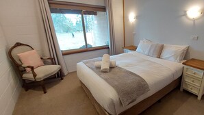 Une chambre à coucher avec un lit, une chaise, une table de chevet et une fenêtre.
