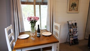 Une table à manger avec une bouteille de vin, un vase de fleurs et des assiettes vides.