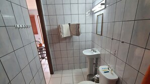 A small bathroom with white tiles, a toilet, a sink, and a towel rack.