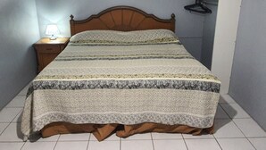 A bedroom with a bed, a nightstand with a lamp, and a wardrobe.