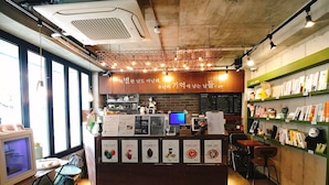 A cafe with a wooden counter, menu boards, and a computer monitor. - Hwon Guest House (Seoul)