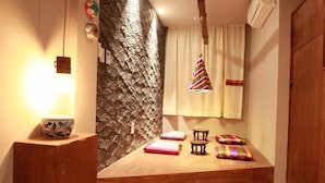 A cozy room with a stone accent wall, a wooden bench, a small table with a bowl, and colorful cushions. - Hwon Guest House (Seoul)