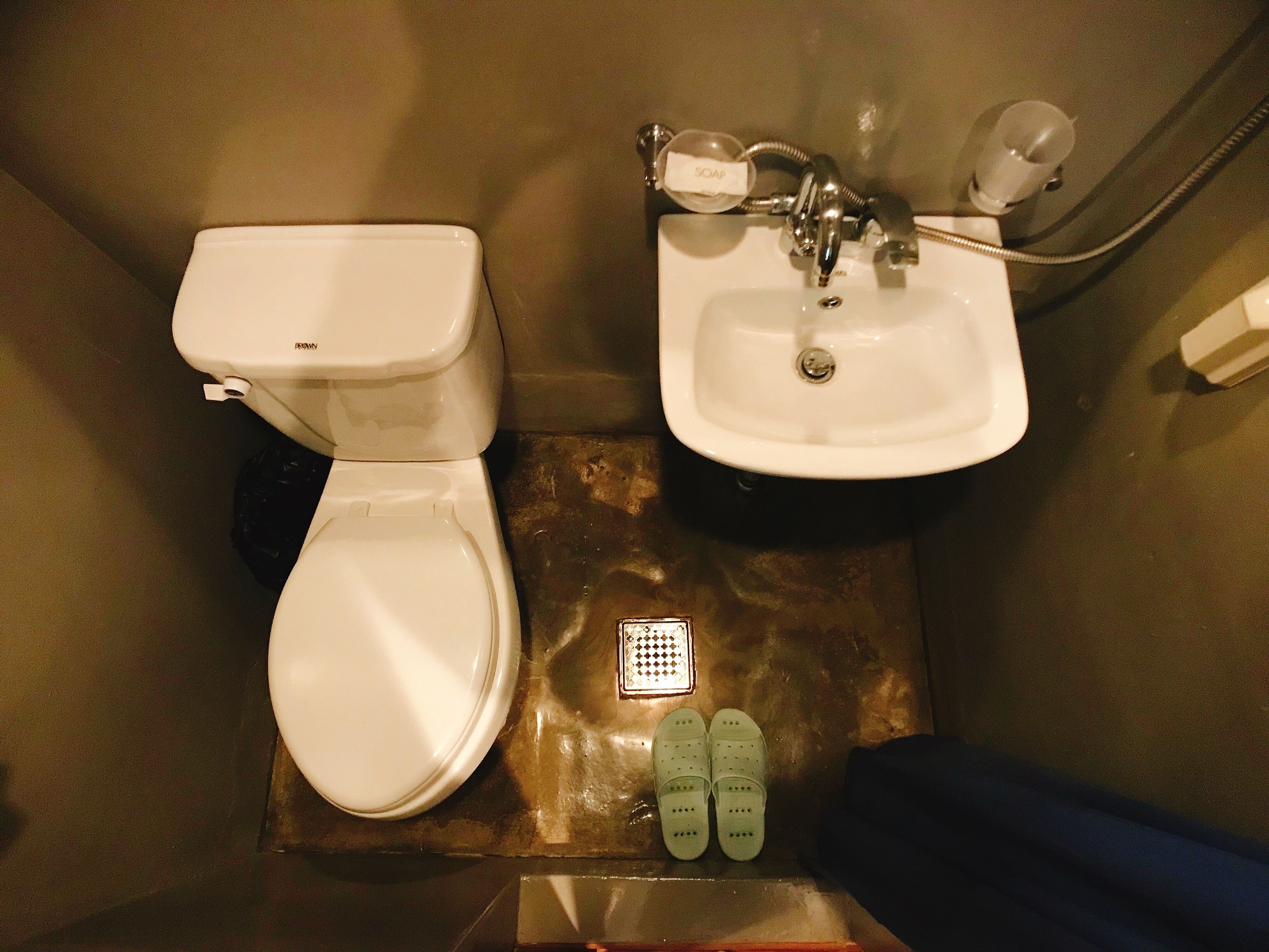 A bathroom with a toilet, sink, and a small drain grate.