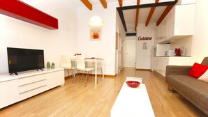 A modern living room with a TV, white furniture, a dining area, and a kitchen. - Lovely and Central Apartment in Palma, Wifi, AC, Balcony, Fully Equipped & Cozy (Palma)