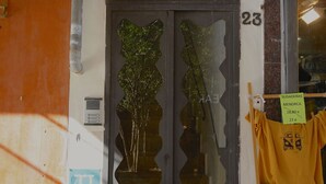 A storefront with a glass door, a sign indicating 'SUDADERAS MENORCA 28,80 e 22 e', and a clothing rack with a yellow shirt and a red garment. - Lovely and Central Apartment in Palma, Wifi, AC, Balcony, Fully Equipped & Cozy (Palma)