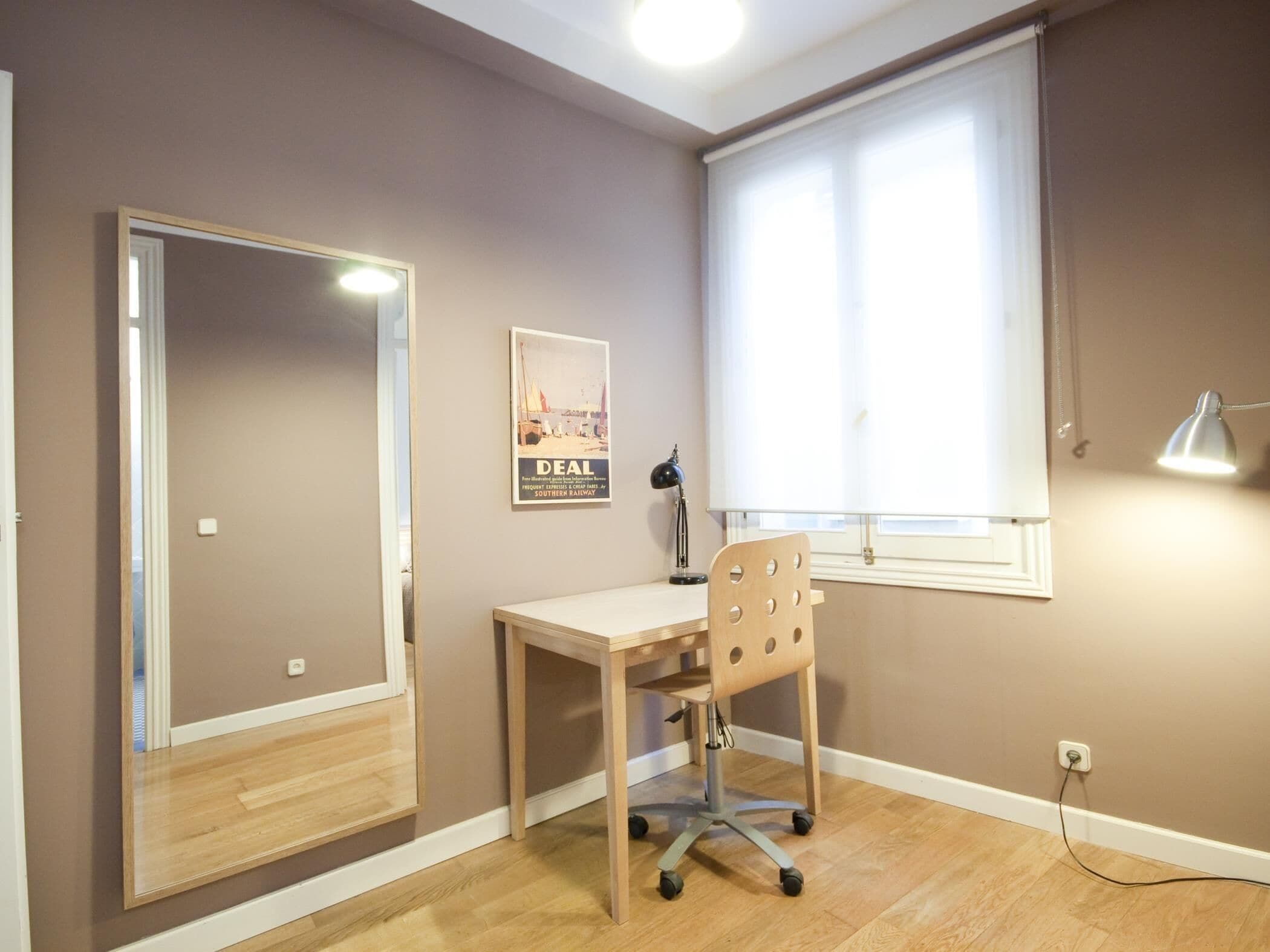 Una habitación con escritorio, silla y un espejo grande.