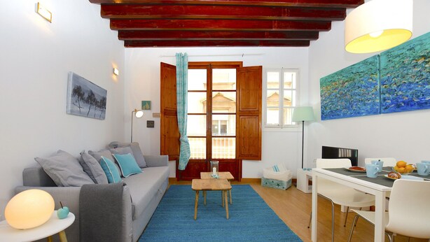 Una sala de estar acogedora con un sofá, una mesa de centro y un comedor con sillas y una mesa.