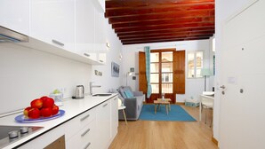 Una cocina moderna con armarios blancos, encimera azul y techo de madera.