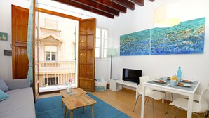 Una sala de estar acogedora con un sofá, una mesa de madera, un televisor y un comedor con sillas.