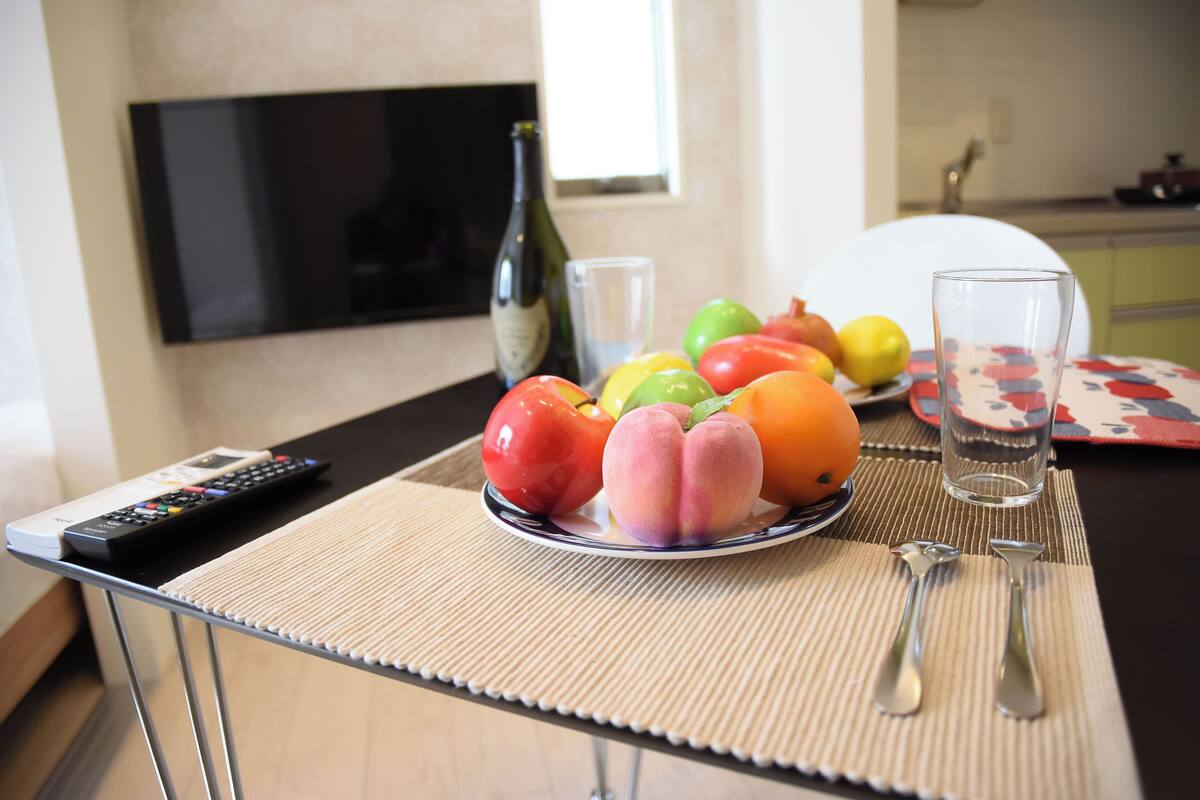 Une table avec une assiette de fruits, une bouteille et une télécommande.