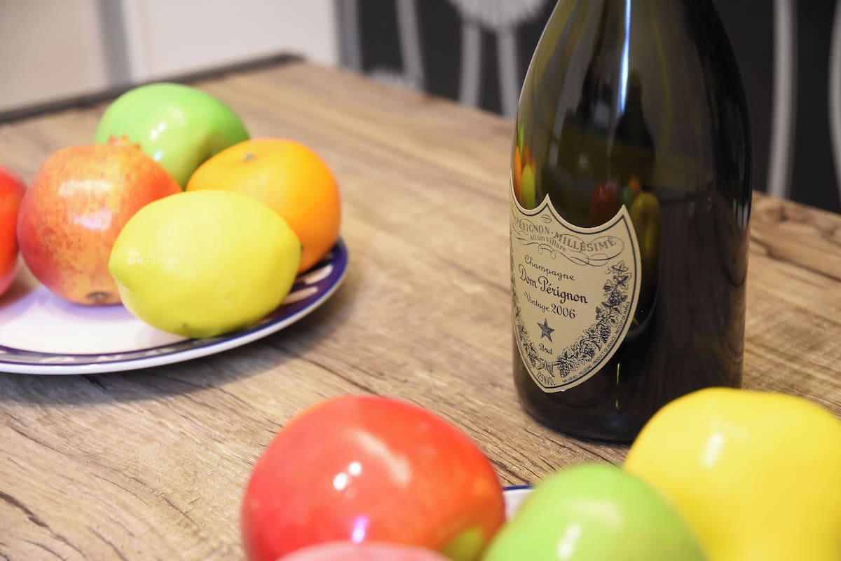 Une bouteille de champagne et une assiette de fruits sur une table en bois.
