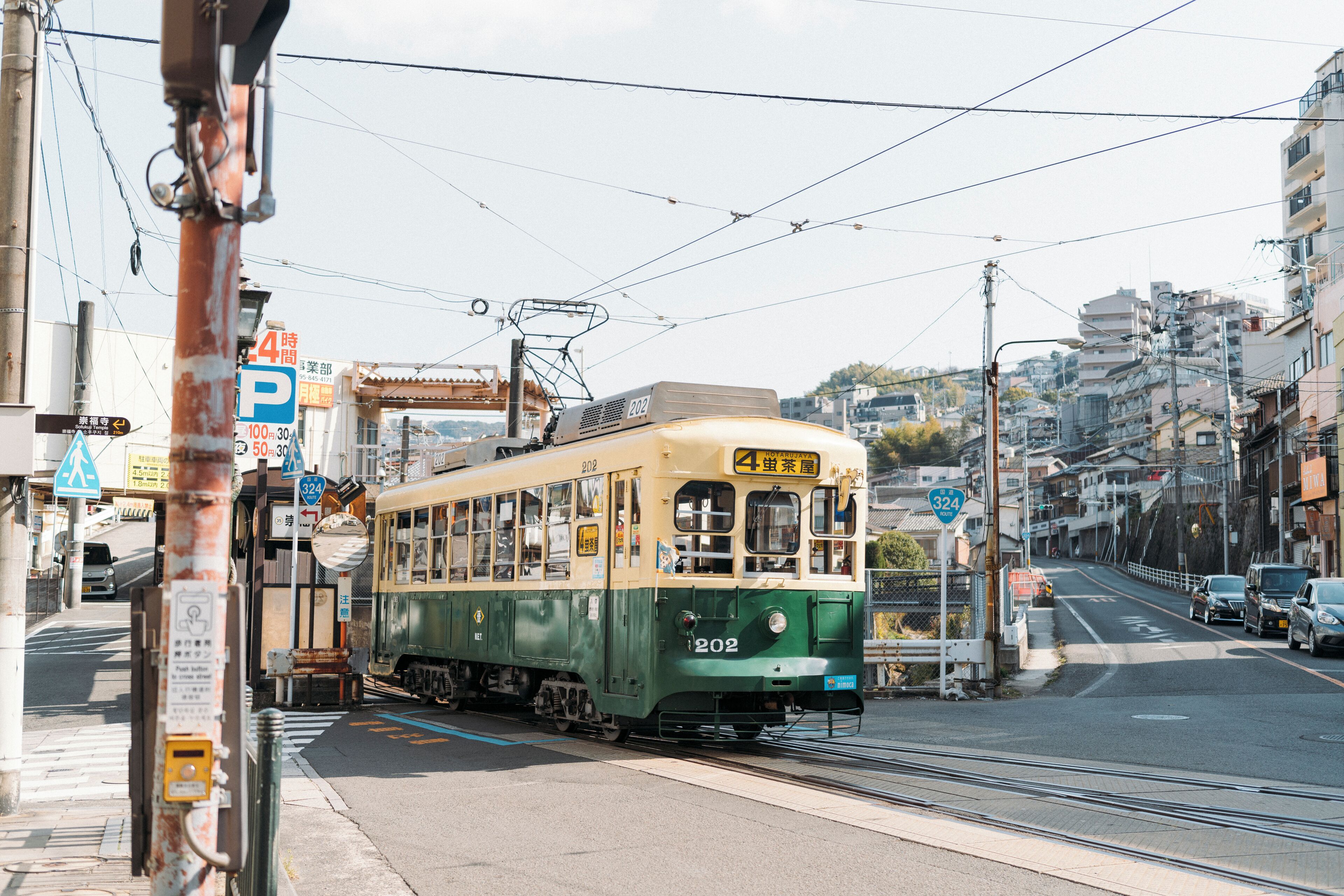 Un tram con il numero 202 che percorre una strada cittadina, con edifici e automobili.
