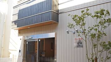 A modern building with a glass entrance, a small tree in the foreground, and a sign on the wall.