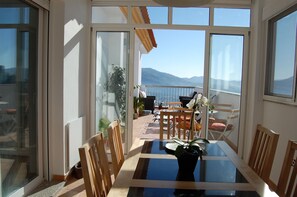 Un comedor con una mesa de vidrio, sillas de madera y una planta en maceta.