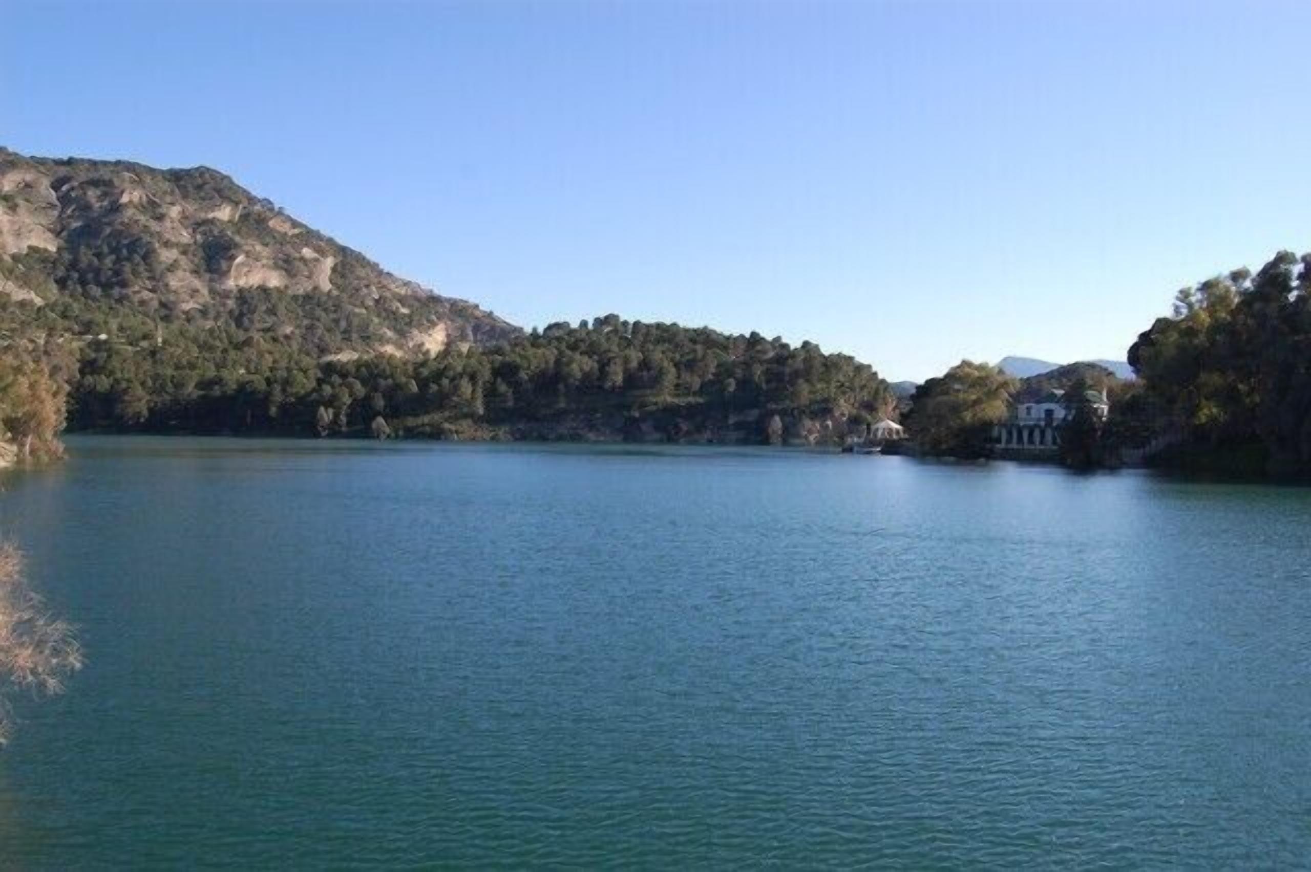 Un lago tranquilo rodeado de colinas con un edificio a la derecha.