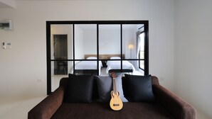 Quarto de hotel moderno com uma cama grande, um sofá pequeno e uma guitarra.