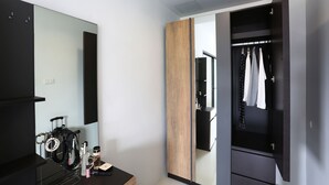 Um banheiro moderno com um espelho grande, um armário de vaidade em madeira e um guarda-roupa preto.